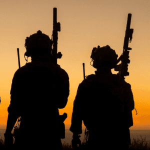 Shooters silhouetted against a sunset at the range